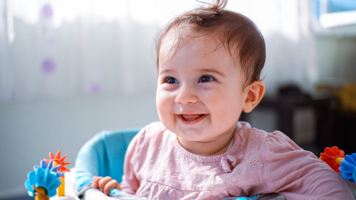 Adorable baby smiling joyfully while playing indoors, capturing pure innocence and happiness.