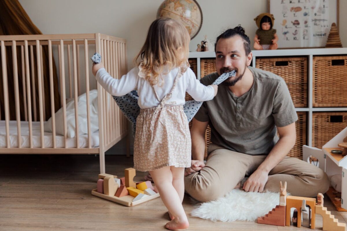 A father and daughter share a playful moment together in a cozy indoor setting.